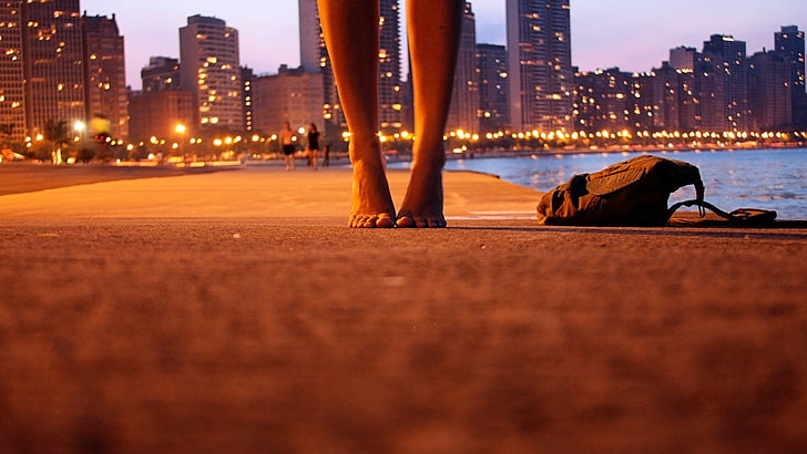 чанта от черен плат, фотография със селективен фокус на крака на човек върху сива бетонова настилка до чанта през нощта, жени, град, бос, боке, гледка на червеи, крака, небостъргач, раници, земя, HD тапет