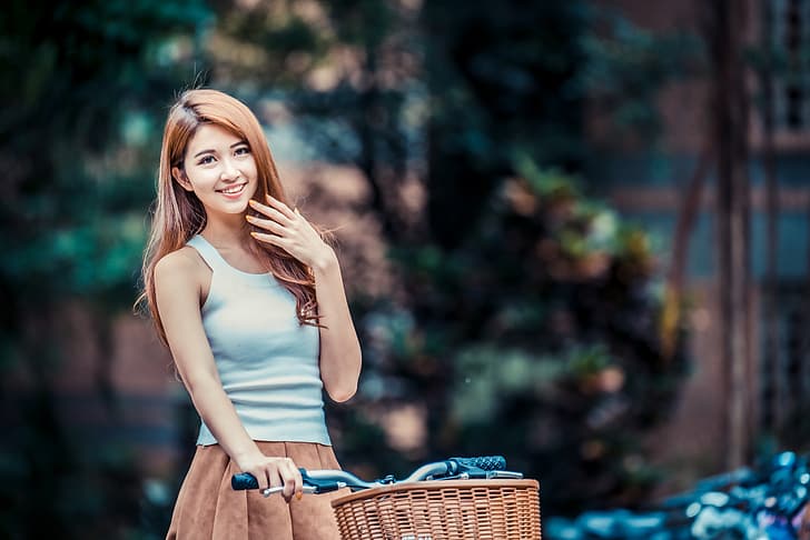 Asian, women, model, depth of field, long hair, brunette, skirt, blue shirt, bycicle, trees, hand on face, looking at viewer, smiling, HD wallpaper