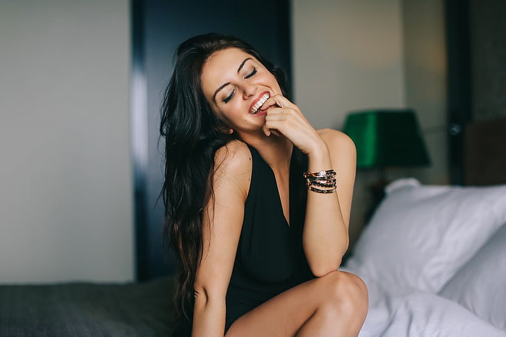 Aurela Skandaj, mujer, modelo, sonriente, dedo en la boca, sentada, ojos cerrados, vestido negro, Fondo de pantalla HD