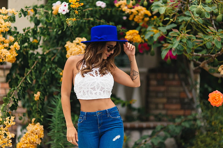 woman in white crop top and blue denim bottoms standing near flowers, Tianna Gregory, women, model, jeans, pants, women with glasses, hat, tattoo, smiling, portrait, HD wallpaper