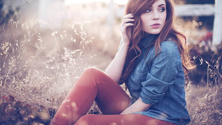 women's blue denim long-sleeved shirt, selective focus photography of woman wearing blue chambray sport shirt and brown leggings, Danielle, redhead, women, freckles, women outdoors, photography, bokeh, model, grass, depth of field, jeans, field, looking away, hands in hair, sitting, long hair, outdoors, touching hair, HD wallpaper