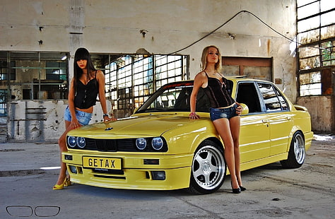 BMW sedán amarillo, chicas, dos chicas guapas, mira a la cámara, de pie cerca del viejo coche amarillo BMW, rubia y morena, Fondo de pantalla HD HD wallpaper