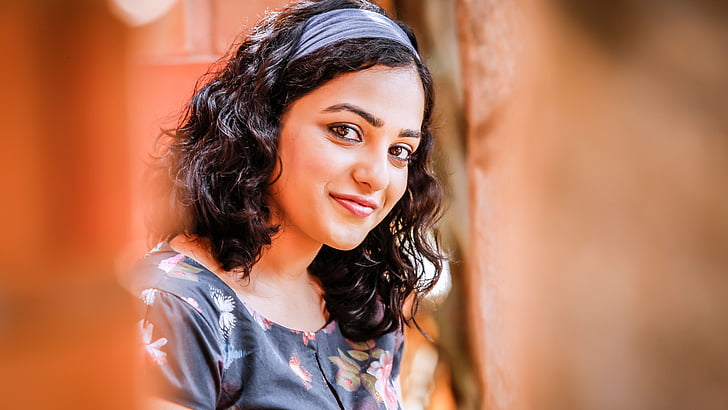 Fotografía de enfoque superficial de mujer con camiseta floral negra mientras sonríe a la cámara durante el día, Nithya Menen, Actriz, Malayalam, Kannada, Telugu, Tamil, HD, 5K, Fondo de pantalla HD