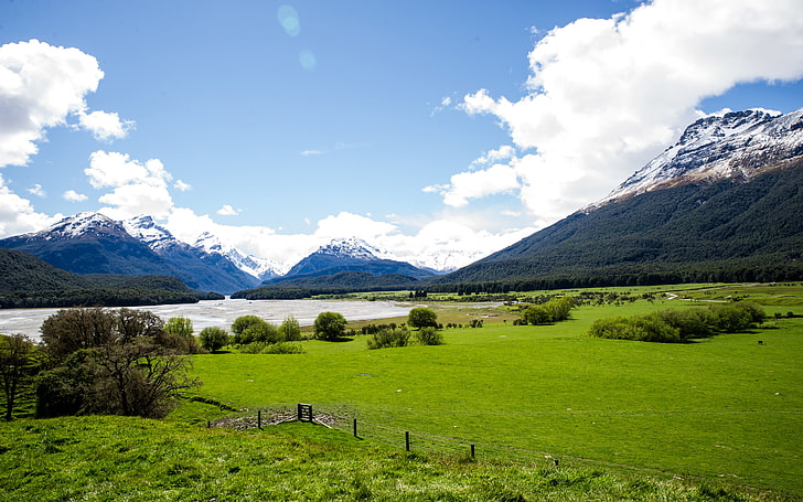 نيوزيلندا المناظر الطبيعية المراعي مع العشب الأخضر ، والغابات الخضراء الكثيفة ، وقمم الجبال مع الثلوج ، وسحابة زرقاء وبيضاء خلفية عالية الدقة عريضة، خلفية HD