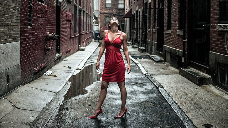 красное платье спагетти с ремешком для женщин, женщины, модель, брюнетка, длинные волосы, женщины на улице, красное платье, взгляд вверх, улица, здание, кирпичи, вода, высокие каблуки, шпилька, мини-платье, декольте, HD обои
