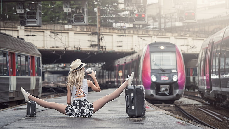 kobieta rozłupująca na szarej betonowej drodze obok pociągu w ciągu dnia, kobiety, blondynka, nogi, kolej, kobiety na zewnątrz, dworzec kolejowy, widok z tyłu, pociąg, kapelusz, spódnica, szpagat, spódniczka mini, Dimitry Roulland, rozciąganie, bagaż, Paryż, Paris Saint Lazare, Tapety HD