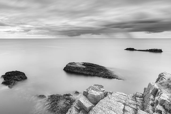 grayscale-photography-of-rocky-mountain-and-body-of-water-out-to-sea
