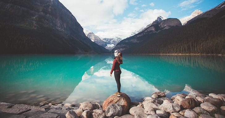 شخص يقف على صخرة أمام مسطح الماء والجبال والطبيعة والمياه والأشجار والثلج والصخور، خلفية HD