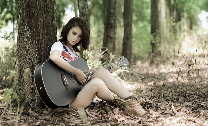 black acoustic guitar, woman in white and red top holding black dreadnought acoustic guitar, women, model, Asian, long hair, musician, guitar, sitting, women outdoors, nature, trees, T-shirt, legs, forest, leaves, playing, HD wallpaper