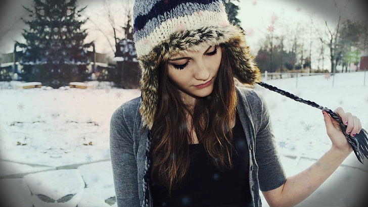 женщина в серой рубашке и синей вязаной шапке смотрит вниз возле сосны, зима, брюнетка, женщины, снег, длинные волосы, накрашенные ногти, лицо, HD обои