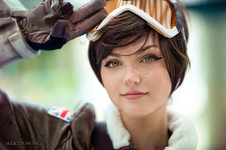 Overwatch Tracer cosplay, woman in brown leather jacket, cosplay, Overwatch, Tracer (Overwatch), women, face, short hair, goggles, bangs, women outdoors, digital art, green eyes, Martin Wong, portrait, makeup, Photoshop, leather jackets, gloves, Union Jack, freckles, Rose Water, HD wallpaper