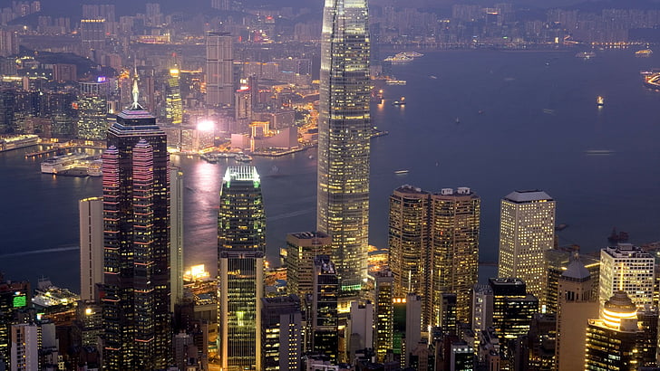 المباني الشاهقة بالمدينة بالقرب من جسم الماء أثناء الليل ، هونغ كونغ ، الصين ، السياحة ، السفر، خلفية HD