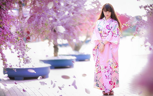 woman wearing floral kimono under cherry blossom, Asian, model, women, brunette, long hair, women outdoors, Japanese clothes, geisha, trees, pink dress, flowers, blossoms, street, blurred, looking away, Japanese women, standing, HD wallpaper HD wallpaper