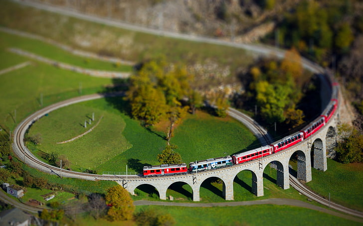 tilt shift photography of trains passing on railway, red train on track miniature, tilt shift, train, Switzerland, arch, landscape, railway, bridge, HD wallpaper