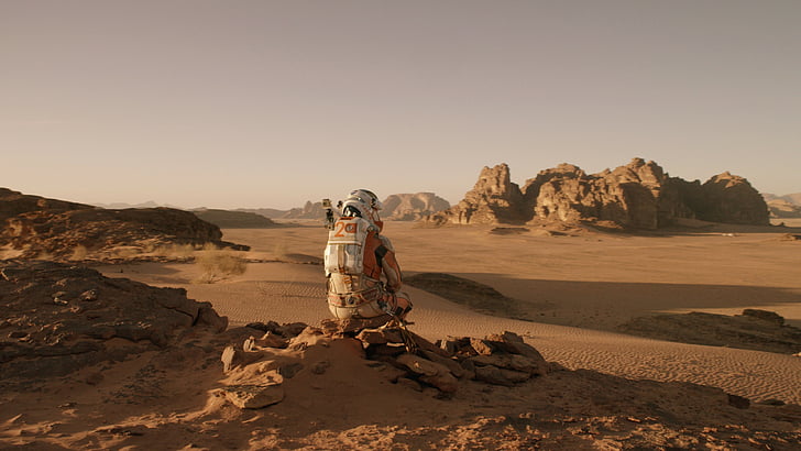 человек в оранжево-белом костюме, сидящий на коричневых скалах вдали коричневое поле и скальное образование днем, Марсианин, Лучшие фильмы 2015 года, фильм Мэтт Дэймон, HD обои