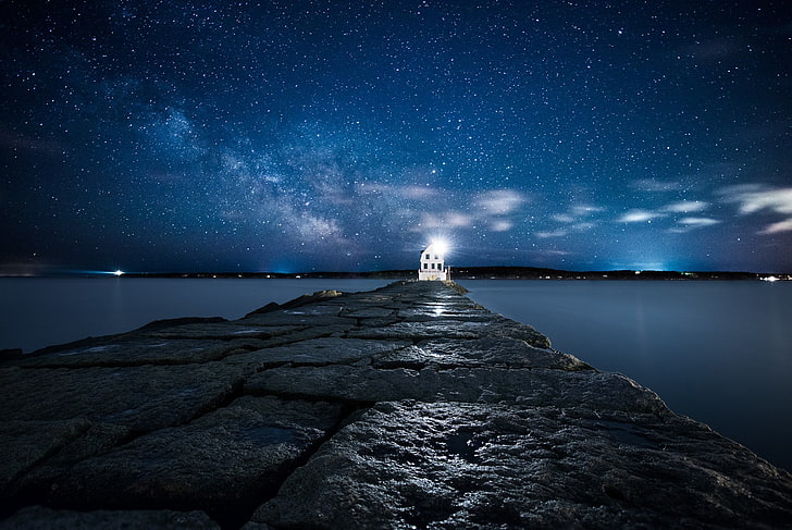 lighted white lighthouse on the edge of rock pavement under blue sky at nighttime, landscape, HD wallpaper