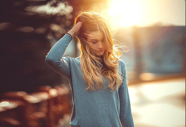women's teal crew-neck long-sleeved shirt, woman in gray long-sleeved top with her right hand on her head, blonde, model, women, looking away, photography, hands in hair, T-shirt, gray, bokeh, sunlight, HD wallpaper