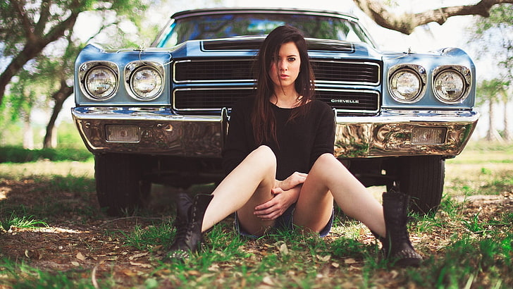 women's black sweatshirt, woman sitting on ground in front of blue Chevrolet Camaro, car, women, Chevrolet Chevelle, brunette, jean shorts, nature, grass, women with cars, Chevelle SS, boots, HD wallpaper
