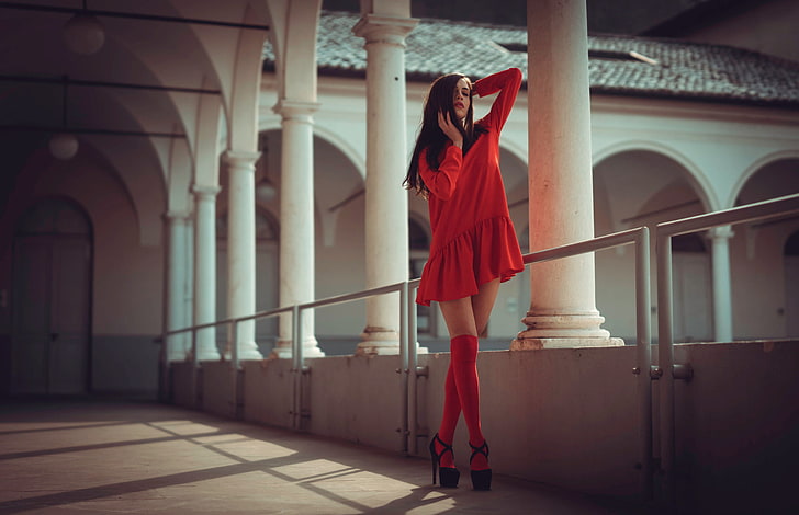 дамска червена рокля с дълги ръкави, жени, брюнетка, жени на открито, балкон, дълга коса, мини-рокля, ръце в коса, високи токчета, високи до коленете, червено червило, червена рокля, стояща, арка, кръстосани крака, Marco Squassina, HD тапет