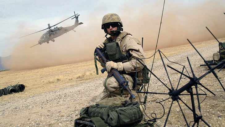 ชายในชุดทหารสีน้ำตาลถือ M4A1 ขณะนั่งบนพื้นในเวลากลางวันกองทัพอากาศสหรัฐฯทหารปืนไรเฟิลภารกิจช่วยเหลือเฮลิคอปเตอร์ลงจอด, วอลล์เปเปอร์ HD