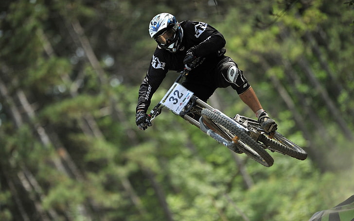 mountain bike racer wearing black-and-white long-sleeved shirt and pants and white full-face helmet soaring on air downhill during daytime, jumping, mountain bikes, bicycle, sport , sports, HD wallpaper