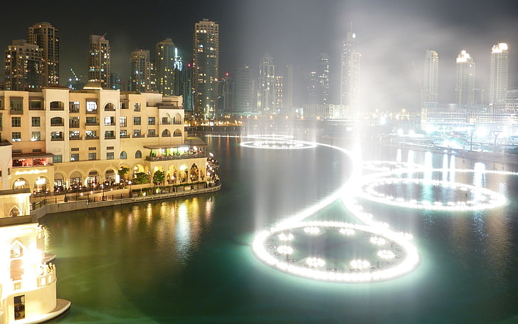 Edificio pintado de color beige junto al cuerpo de agua con agua danzante, ciudad, paisaje urbano, Emiratos Árabes Unidos, Dubai, noche, Fondo de pantalla HD