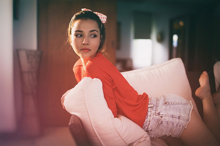 brown eyes, hair ribbon, Paul Toma, kneeling, brunette, red clothing, couch, women, jean shorts, sitting, HD wallpaper