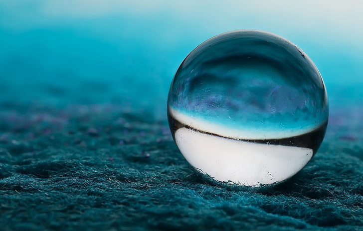لعبة رخامية بيضاء وزرقاء ، كرة زجاجية شفافة فوق التربة الزرقاء ، العشب ، الكرة ، الماكرو ، التصوير الفوتوغرافي ، الكرة، خلفية HD