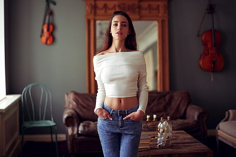 women's white off-shoulder long-sleeved top and blue bottoms, women, jeans, portrait, chair, couch, depth of field, white sweater, hands in pockets, short tops, women indoors, brunette, standing, model, HD wallpaper HD wallpaper