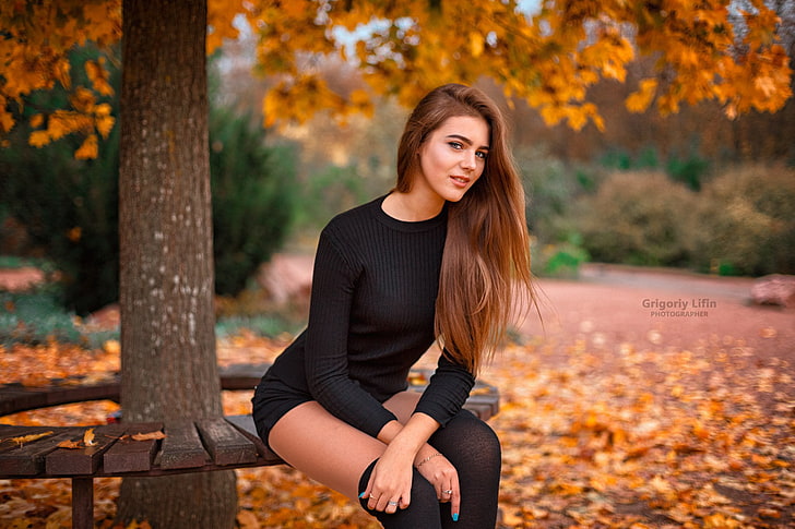 women's black long-sleeved dress, woman sitting on a wooden bench under a tree, women, Grigoriy Lifin, black stockings, trees, leaves, sitting, women outdoors, smiling, black clothing, long hair, depth of field, painted nails, black sweater, looking at viewer, brunette, HD wallpaper
